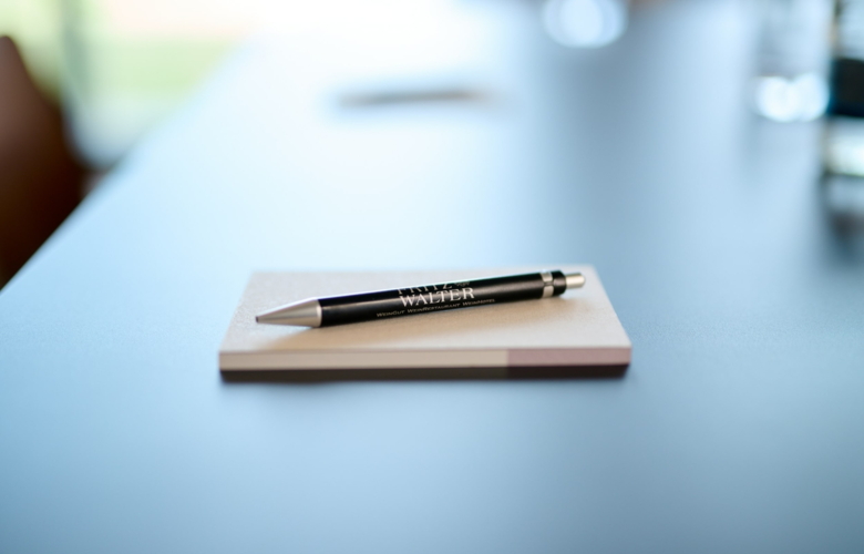 Schwarzer Kugelschreiber mit silbernen Details und Aufdruck 'FRITZ WALTER' liegt auf einem Notizblock auf einem hellen Tisch.