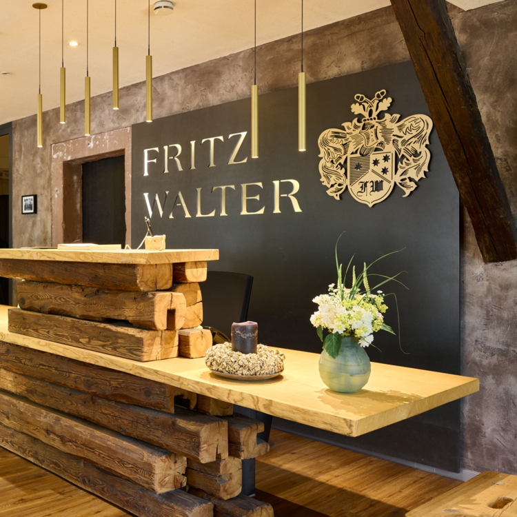 Eine moderne Rezeption aus Holz mit einer eleganten Abdeckung. Im Hintergrund ist das Logo "FRITZ WALTER" deutlich sichtbar.