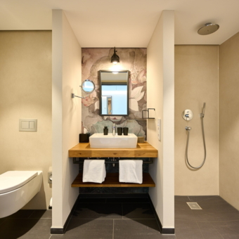 Badezimmer im Superior Zimmer. Links die Toilette, mittig das Waschbecken und rechts die Dusche.