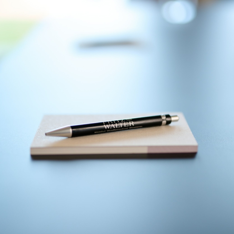 Schwarzer Kugelschreiber mit silbernen Details und Aufdruck 'FRITZ WALTER' liegt auf einem Notizblock auf einem hellen Tisch.
